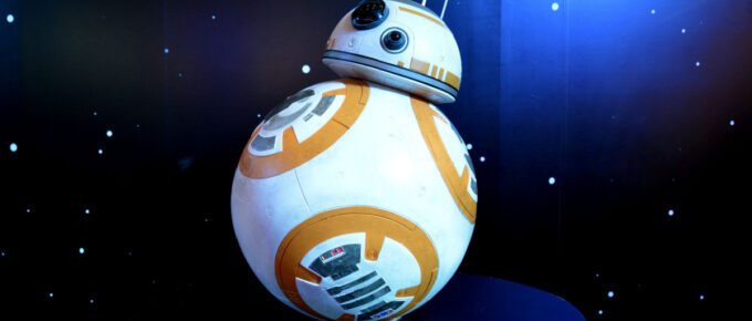 BB-8 android model on a black table with black and blue light background.