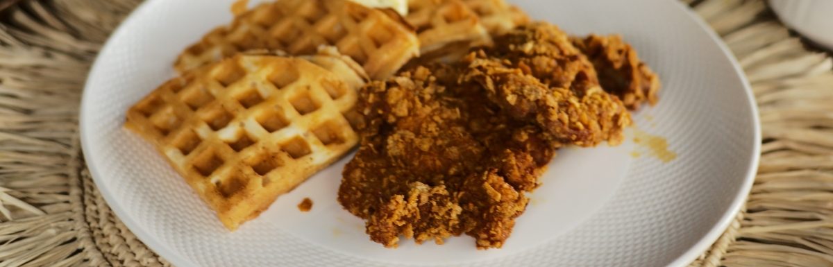 Delicious chicken and waffles on a white plate.
