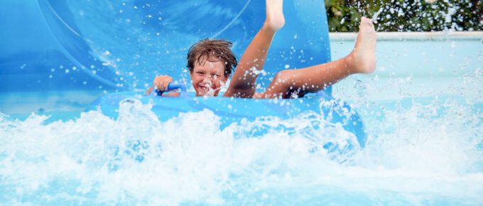 An 8 year old boy is riding in the water Park on inflatable circles on water slides with splash.
