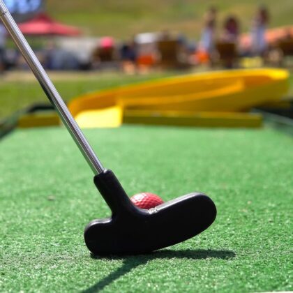 Closeup of player play mini golf with red ball.
