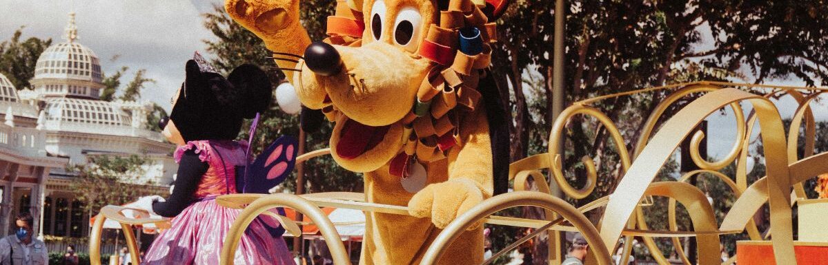 Pluto standing near the crowd in Disney world during a parade.