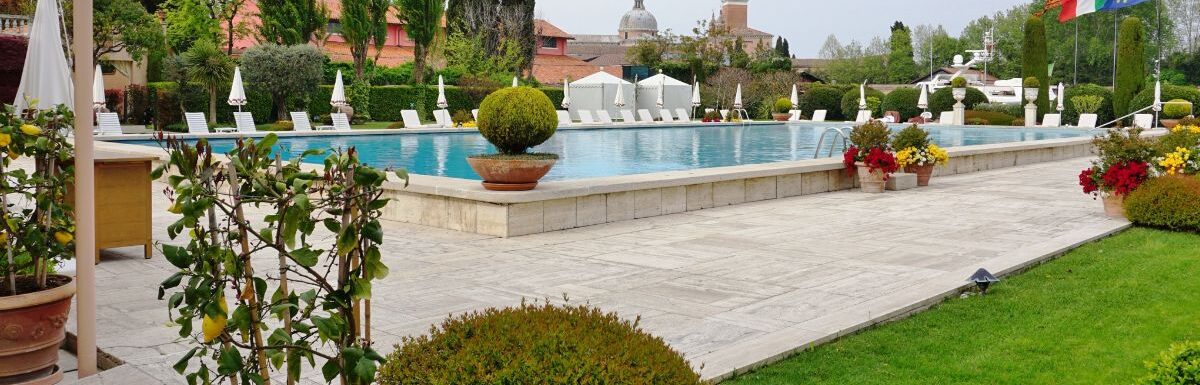 Pool area with green plants and grass around in the Belmond Hotel Cipriani, on the Giudecca in Venice, is one of the most expensive hotels in the world.