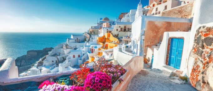 Picturesque view of traditional Cycladic Santorini houses on small street with flowers in foreground in Santorini, Greece.