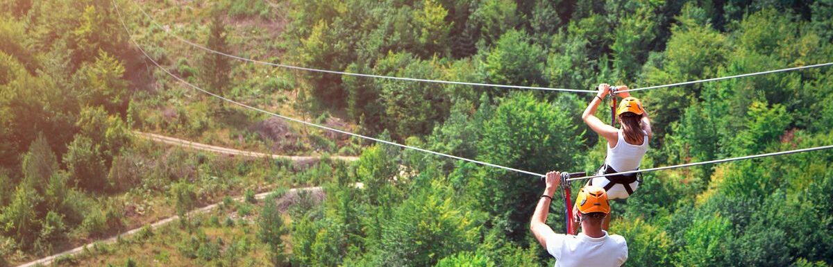 Tourists ride on the Zipline wearing white shirts and helmet.